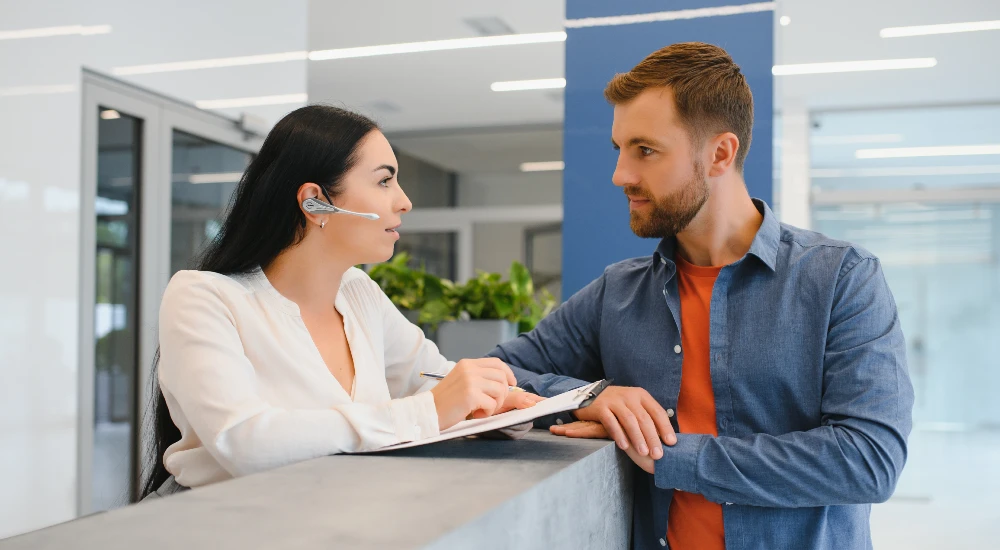 friendly-woman-talking-to-the-client-at-reception-desk
